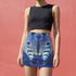 A high-waisted, bodycon mini skirt with a tight, fitted silhouette ending mid-thigh. The skirt features a vibrant, all-over graphic print of a mirrored zebra head in electric and royal blue tones against a dark blue, pixelated background. The zebra's stripes have a textured, glittery appearance in shades of silver and light blue. The skirt is made from a smooth, stretchy performance knit fabric with a subtle sheen, designed to hug the body's curves.